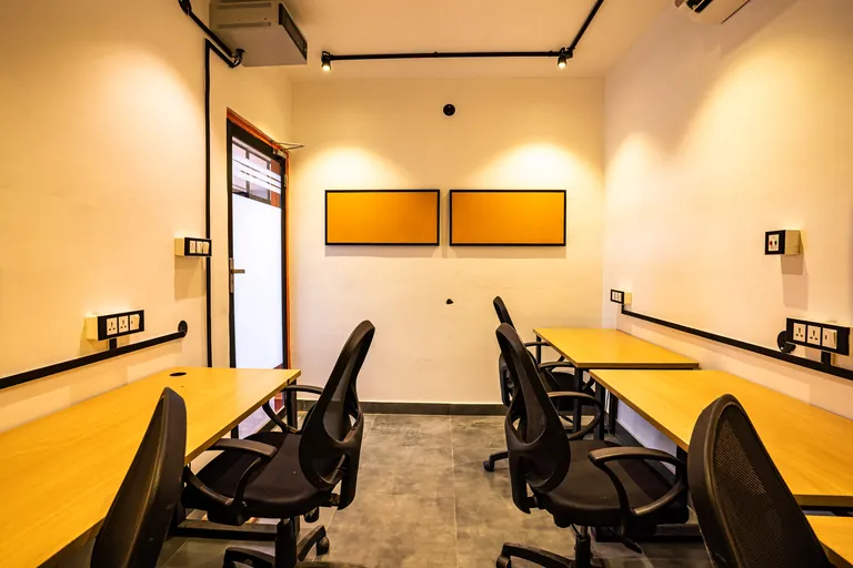 Enclosed cabin with desks along both walls at Suits Mansarovar