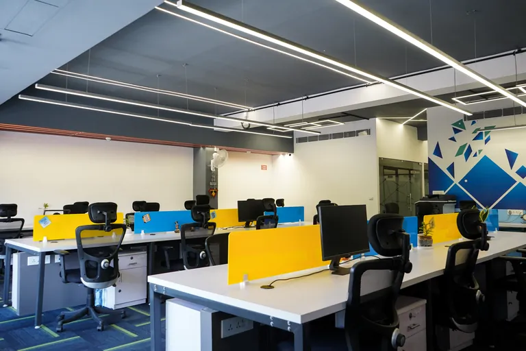 Open workstations with blue and yellow desk dividers at Suits Vaishali Nagar